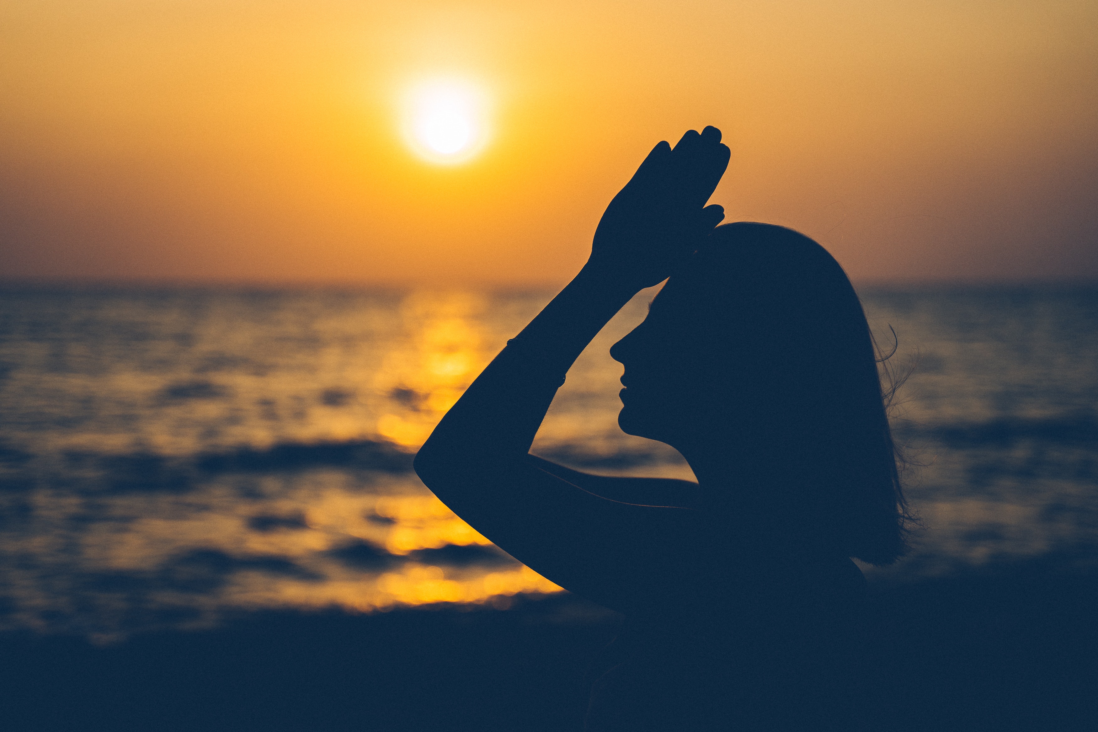 woman meditating on the beach at sunset