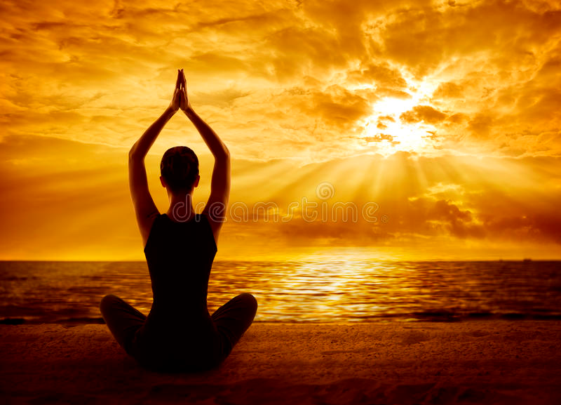 a woman meditating at sunset